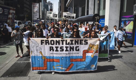 Protestors in New York hold a banner which says 'Frontlines Rising', as they protest oil and gas projects across the US Gulf South.